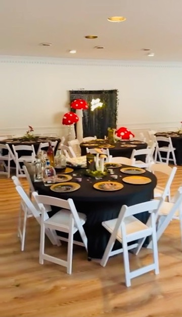 Whimsical wonderland party setup with themed backdrop, gold chargers, and celebration tables