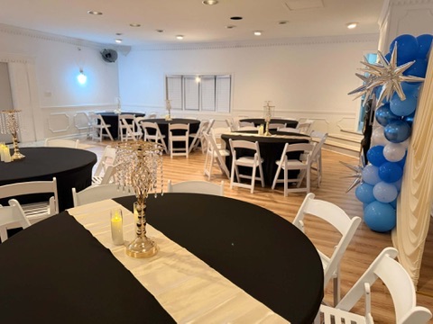 Celebration setup with black linens, gold runners, and celestial star balloon arch