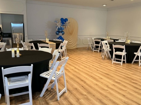 Spacious salon floor with hardwood finishes, dressed dining tables, and party decor