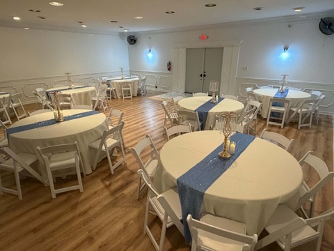Banqueting hall arranged with ivory tablecloths, sparkle blue runners, and candelabra centerpieces